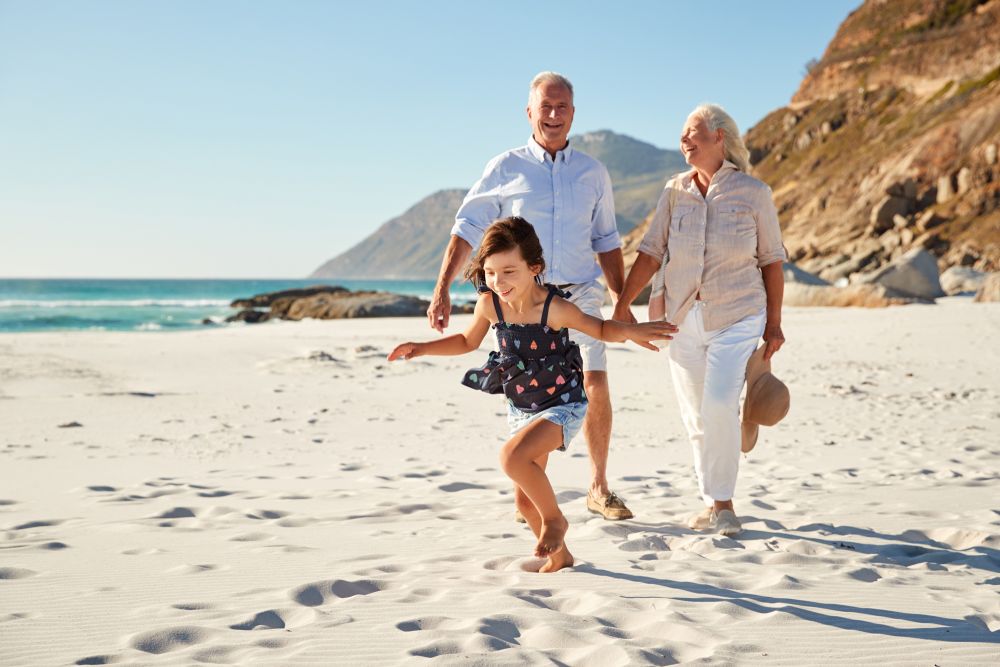 Seniorzy z wnuczką spacerujący po plaży